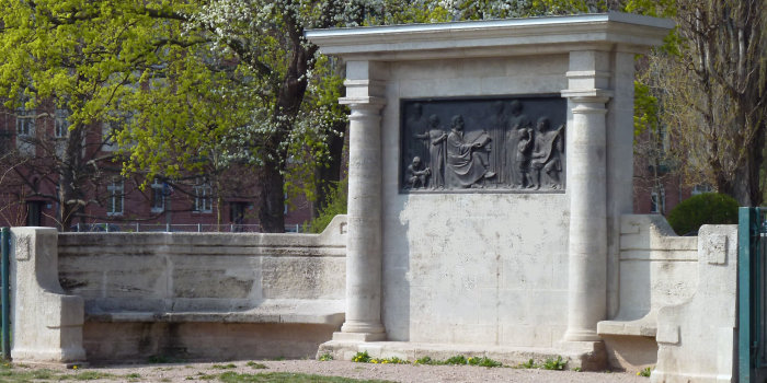 Ein Denkmal in Halbkreisform mit Sitzmöglichkeit und mit einem Bronzerelief