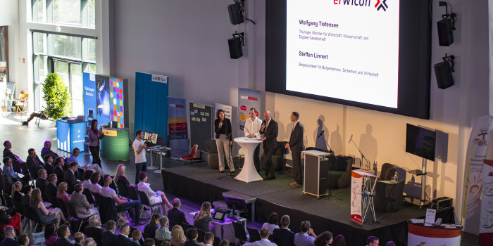 Foto: Erfurter Wirtschaftskongress 2017 © Stadtverwaltung Erfurt Viele Personen sitzen in einem Saal vor einer Bühne, auf der Bühen sprechen Leute