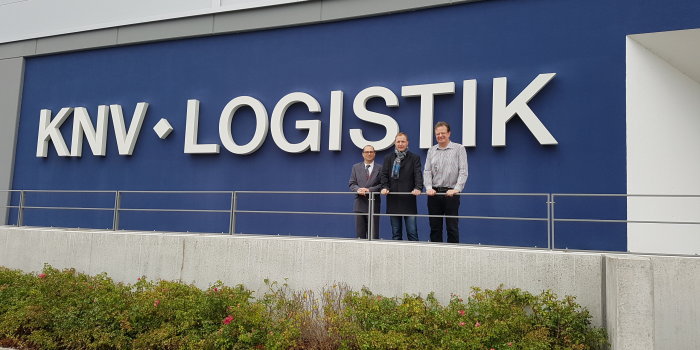 Steffen Linnert und Wolfgang Jentz stehen mit Sven Göhring vor KNV Logistik-Logo