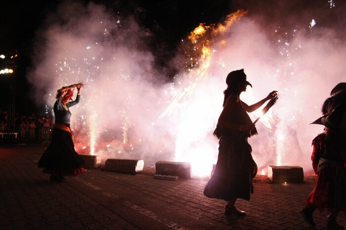 Zwei als Hexen verkleidete Frauen stehen mit Besen neben einem brennenden Feuer