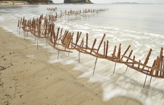 eine Holzkonstruktion als stilisierte Grenze am Meeresstrand