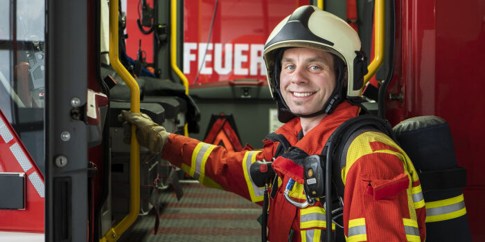Ein Mann in Feuerwehrausrüstung steht an der Tür eines Feuerwehrfahrzeuges.