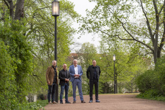 vier Männer stehen unter einer Laterne in einer Grünanlage