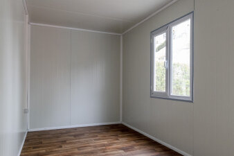 ein schlichter heller Raum mit Fenster und Boden in Holzoptik