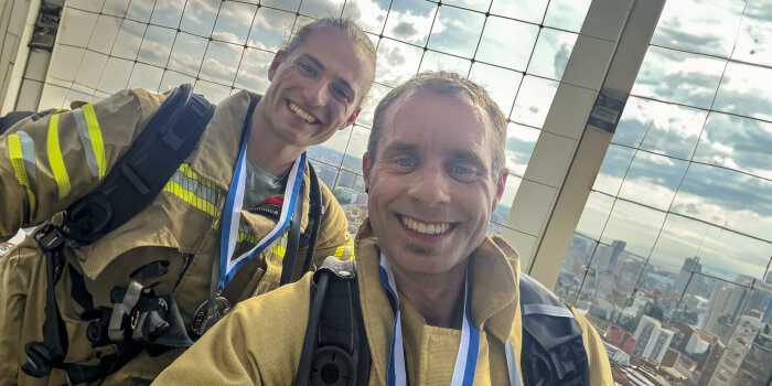 Zwei Männer in Feuerwehrkleidung stehen zusammen und lächeln. 