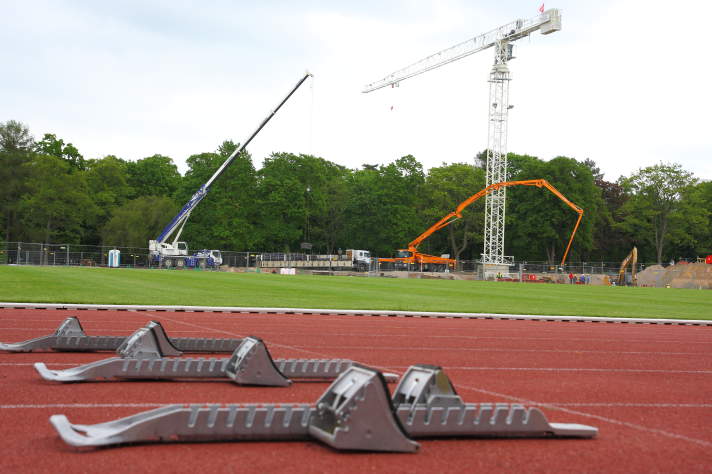 Startblöcke auf Tartanbahn, im Hintergrund eine Stadionbaustelle.