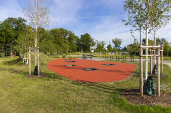 eine Trampolinlandschaft in einem Park, im Boden sind fünf rechteckige Trampoline eingelassen