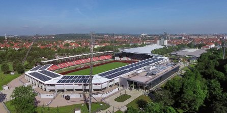 Ein Stadion mit einem angrenzenden Gebäude aus der Vogelperspektive aufgenommen