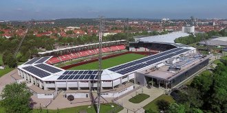 Ein Stadion mit einem angrenzenden Gebäude aus der Vogelperspektive aufgenommen