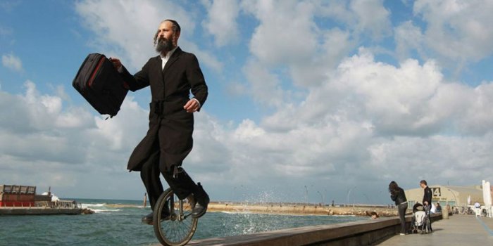 Jüdische männliche Person mit Schläfenlocken fährt mit einem Einrad auf der Kaimauer