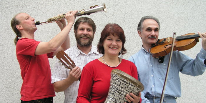 Drei Männer und eine Frau mit Musikinstrumente in den Händen, die in einer Gruppe zusammenstehen