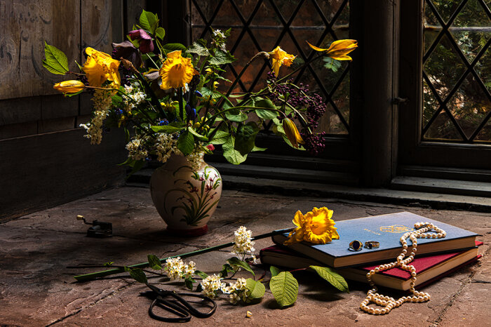 Ein Tisch mit einem Blumenstrauß und ein paar Büchern in einem dunklen Raum