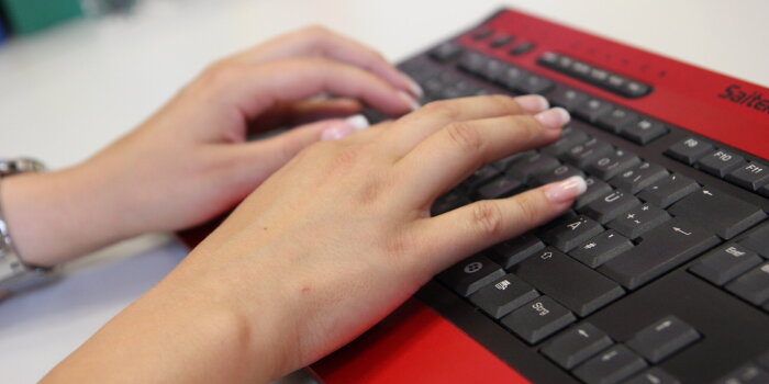 Das Bild zeigt eine Tastatur sowie einen Mitarbeiter beim Tastschreiben.