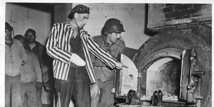 Ein befreiter Häftling zeigt einem Soldaten der US-Armee einen im Krematorium des Konzentrationslagers 