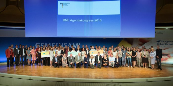 Gruppenbild auf Bühne vor Präsentationsleinwand