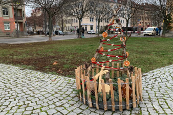 ein rundes, in einen niedrigen Holzzaun eingefasstes, weihnachtliches Arrangement