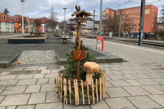 ein rundes, in einen niedrigen Holzzaun eingefasstes, weihnachtliches Arrangement