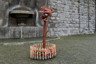 ein rundes, in einen niedrigen Holzzaun eingefasstes, weihnachtliches Arrangement