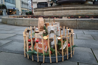 ein rundes, in einen niedrigen Holzzaun eingefasstes, weihnachtliches Arrangement