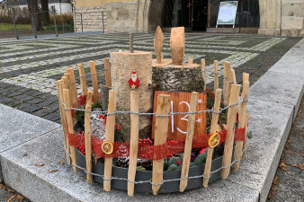 ein rundes, in einen niedrigen Holzzaun eingefasstes, weihnachtliches Arrangement