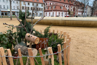 ein rundes, in einen niedrigen Holzzaun eingefasstes, weihnachtliches Arrangement