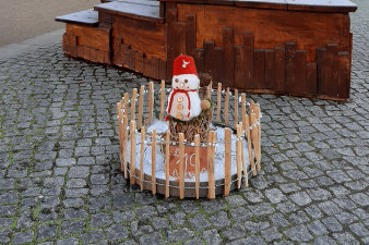 ein rundes, in einen niedrigen Holzzaun eingefasstes weihnachtliches Arrangement