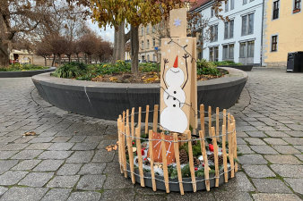 ein rundes, in einen niedrigen Holzzaun eingefasstes, weihnachtliches Arrangement