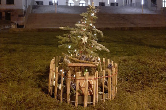 ein rundes, in einen niedrigen Holzzaun eingefasstes, weihnachtliches Arrangement