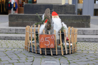 ein rundes, in einen niedrigen Holzzaun eingefasstes, weihnachtliches Arrangement