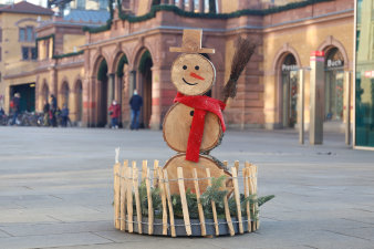 ein rundes, in einen niedrigen Holzzaun eingefasstes, weihnachtliches Arrangement