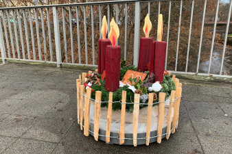 ein rundes, in einen niedrigen Holzzaun eingefasstes weihnachtliches Arrangement