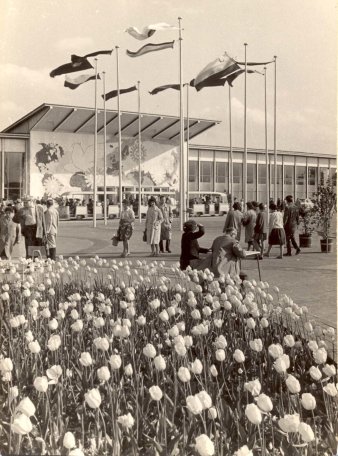 Menschen auf dem Gelände mit Hallen, Fahnen und Blumen