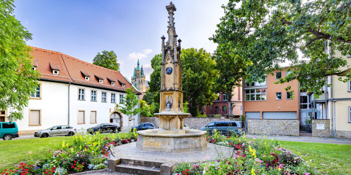 Brunnenanlage mit Türmchen, umgeben von einem Blumenbeet