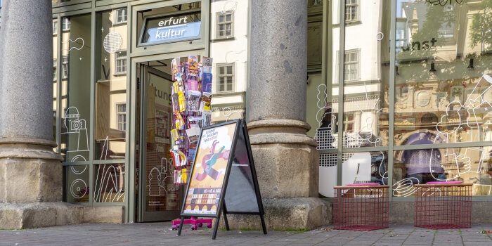 Glasfront eines Ladengeschäfts, davor ein Aufsteller