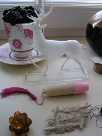 mehrere kleinere Gegenstände auf Tisch, im Zentrum ein weißer Glashirsch