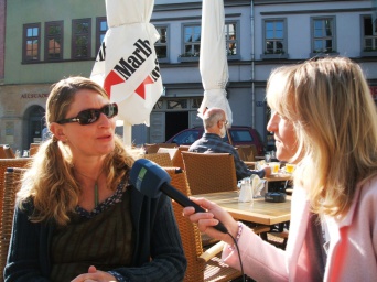 zwei Frauen am Cafétisch draußen mit Mikrofon