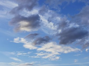 graue und weiße Wolken kreuzen sich vor blauem Hintergrund