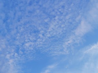 weiße wattebauschartige Wölkchen vor strahlend blauem Hintergrund