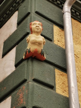 kleine Gallionsfigur an Hausecke, barbusig mit starrem forderndem Blick und flacher Nase