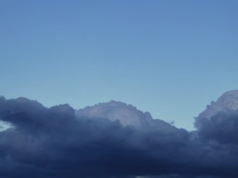in der unteren Bildhälfte dunkelblaue kompakte Wolke mit bogenförmiger Kante vor hellerem Hintergrund