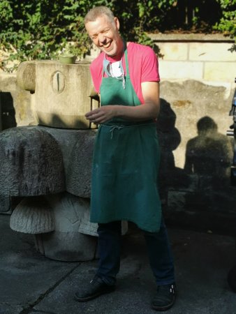 lachender Mann mit pinkem T-Shirt und grüner Schürze