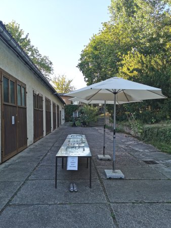 3 Stahltische mit den Exponaten, 2 Sonnenschirme auf dem Hof der Künstlerwerkstätten
