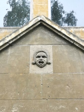 Türgiebel mit schreiendem Gesicht und merkwürdiger Lockenfrisur