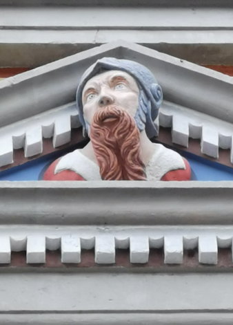 Figur mit Helm und lockigem roten langem Bart in Fenstergiebel