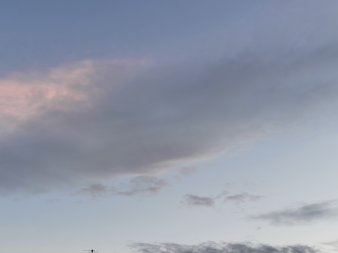große rosa-graue Wolke mit diffusem Umriss vor grau-blauem Hintergrund