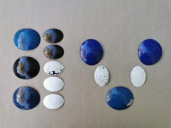5 größere aufgetiefte Ovale mit blauer und schwarzer Emaille-Oberfläche und 7 kleinere, meist Weiße auf grauem Papi