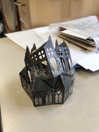 eine filigranes Metallkonstrukt in Schwarz, das in Form einer Fassade mit Kirchenfenstern gearbeitet ist