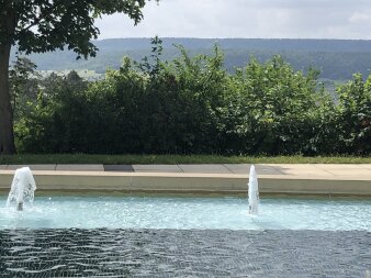 Pool mit Springbrunnen und viel Grün und Bergen im Hintergrund
