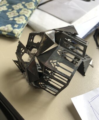 eine filigranes Metallkonstrukt in Schwarz, das in Form einer Fassade mit Kirchenfenstern gearbeitet ist