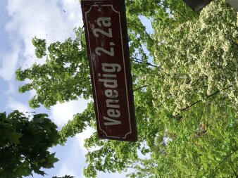 rotes Straßenschild "Venedig 2, 2a" in grüner Umgebung